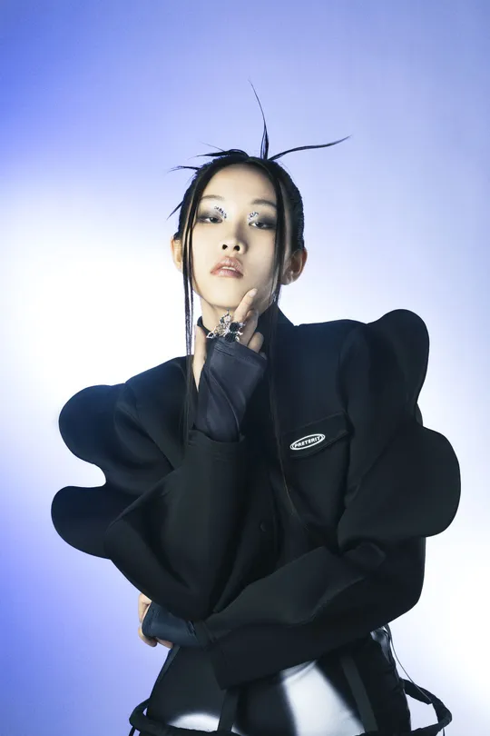 一位戴黑色手套的女子在蓝色背景前摆姿势