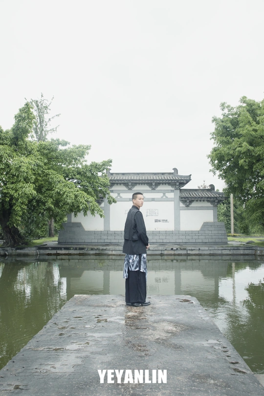 一位穿着和服的男子站在池塘边