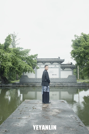 一位穿着和服的男子站在池塘边