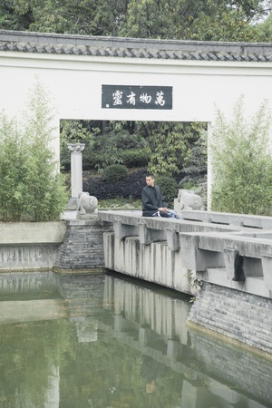 一个坐在小池塘上的桥上的男人