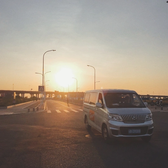 日落时的高速公路 路上有汽车行驶 路边停着一辆白色SUV。