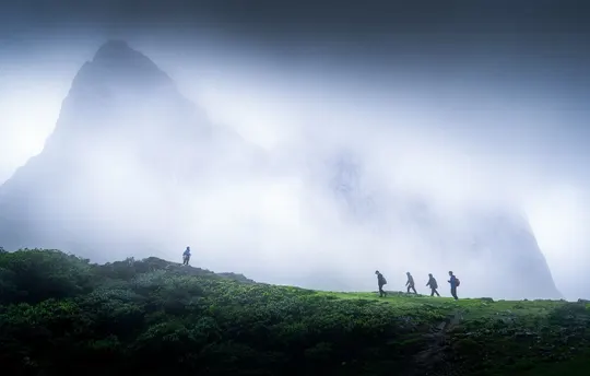 雾中一群人沿着山坡向上走