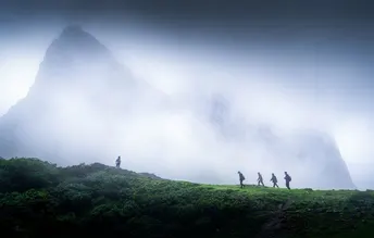 雾中一群人沿着山坡向上走