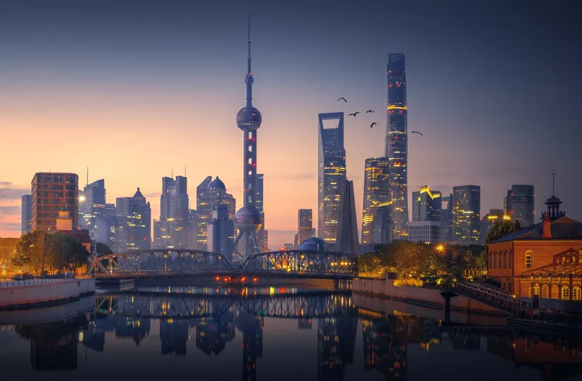 黄昏或日落时的一座城市 天空中有着摩天大楼和其他建筑 河上有一座桥。