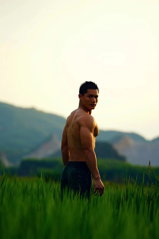 站在一片高草丛中的年轻男子 背景是山脉。