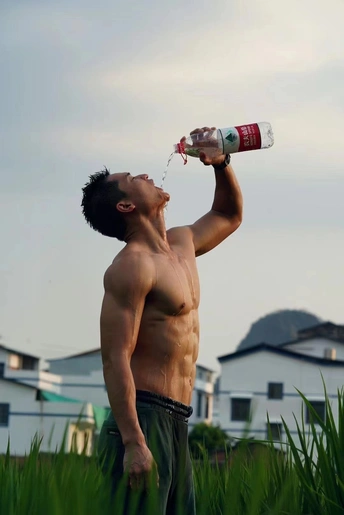 一位年轻男子在草地上喝着一瓶水