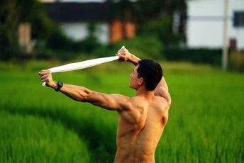 一张男子在绿地上展示肌肉的照片