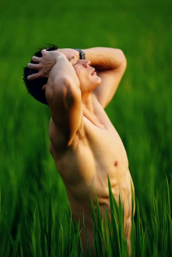 一位年轻男子举着手臂站在绿草地上