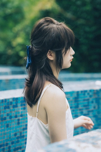 站在蓝色游泳池旁的一位年轻女子