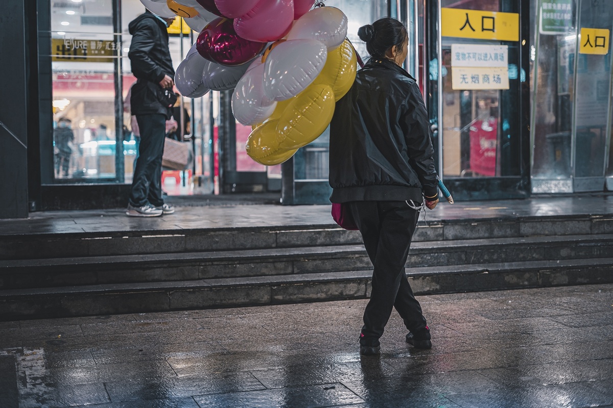 香港街头 一名男子从一名卖气球的女子身边走过