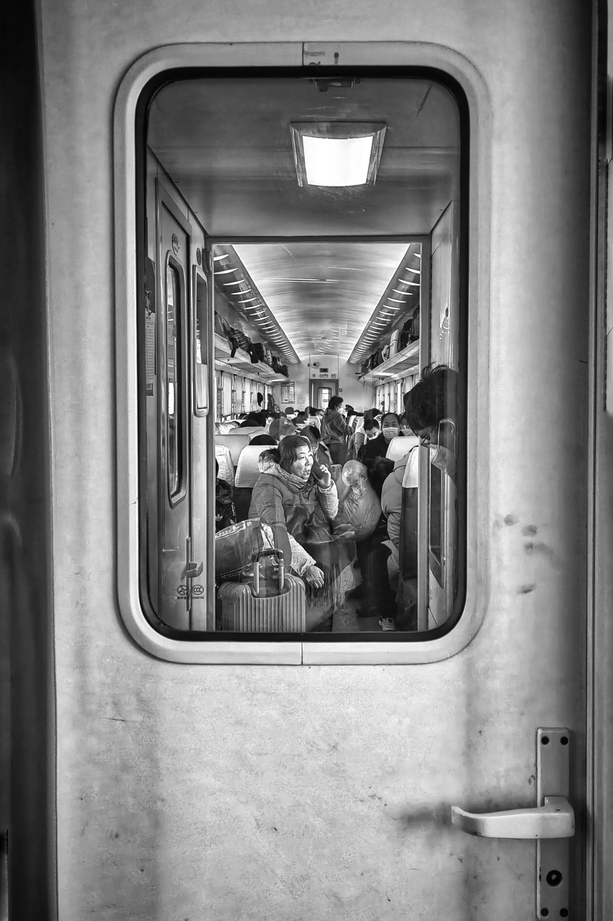 一张黑白照片 地铁列车上的人们带着行李 门和窗户
