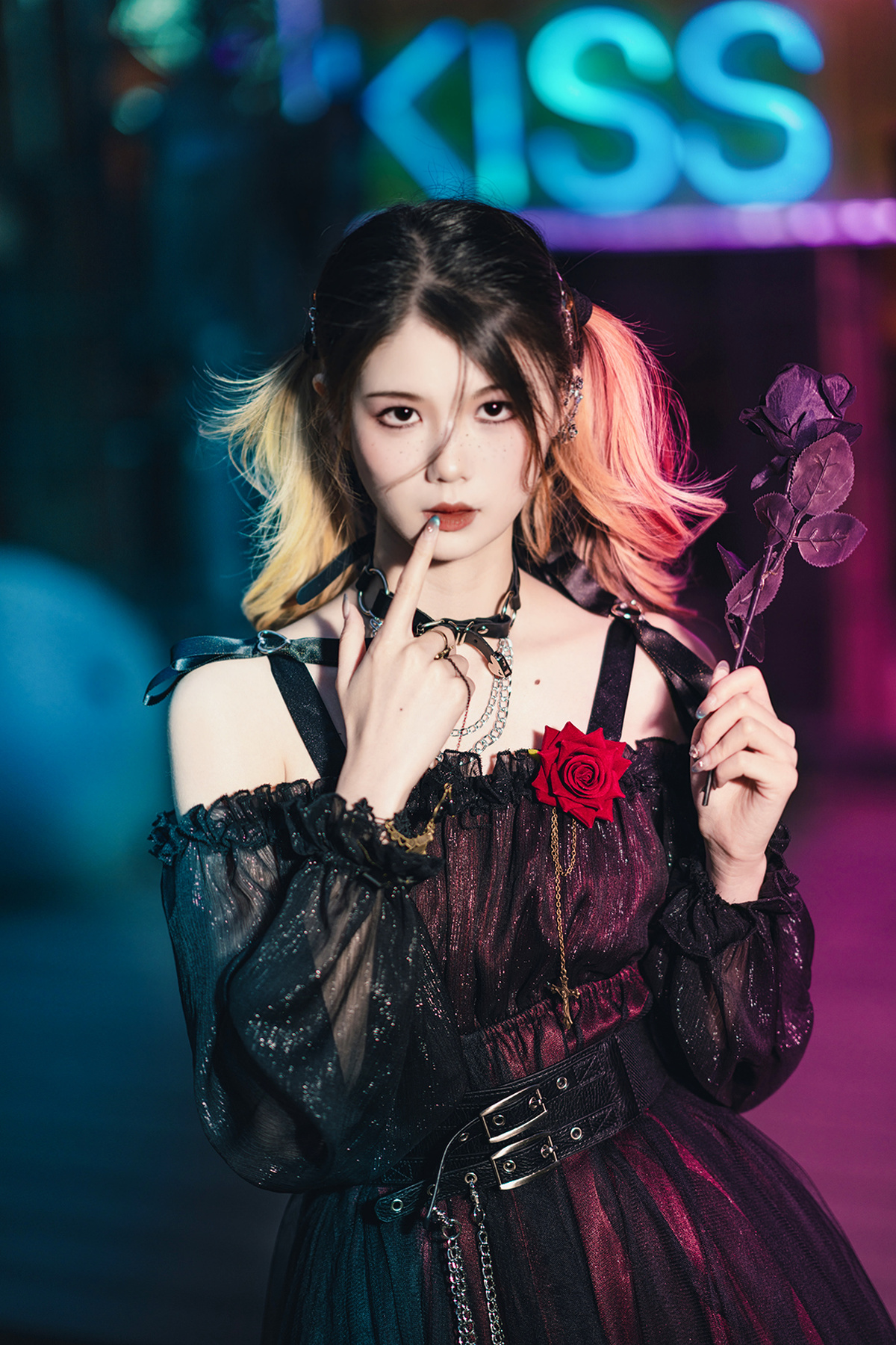 一个穿着黑色连衣裙的年轻女子手拿粉色玫瑰 在街上吸烟。