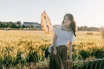 一位年轻女子拿着风筝站在田野里