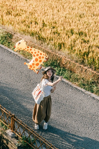 一位年轻女子带着风筝走在路上