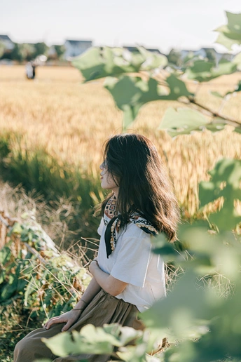 一位年轻女子坐在麦田里 眺望着远方