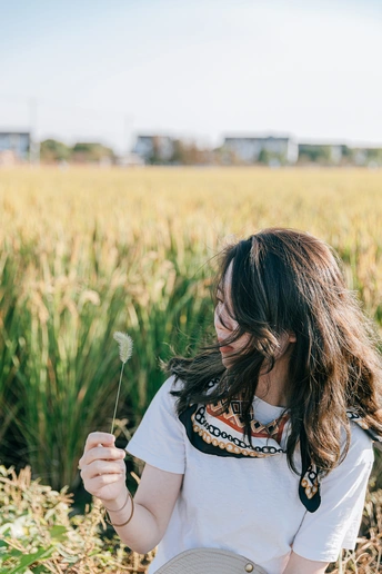一位年轻女子站在田野中 手里拿着一盘盘食物。