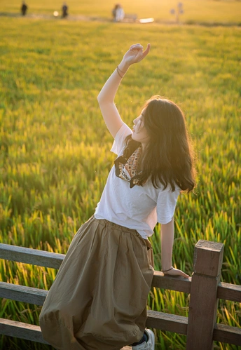 一个年轻女子穿着裙子坐在木凳上 举起双手向天空。