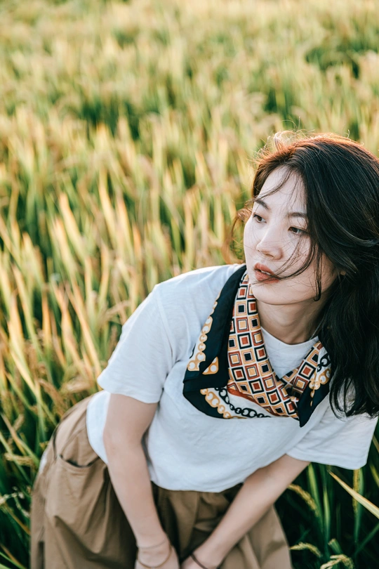 一个年轻女子坐在草地上 背景中站着一个人。