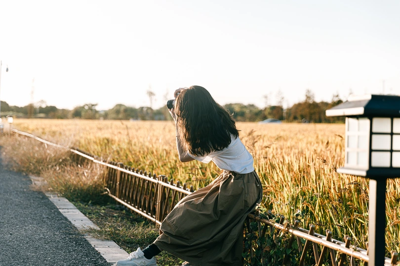 站在公路边 靠近围栏和田野的年轻女子