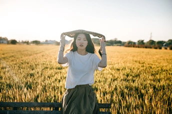 一位年轻女子坐在麦田中的长凳上 双手举过头顶。