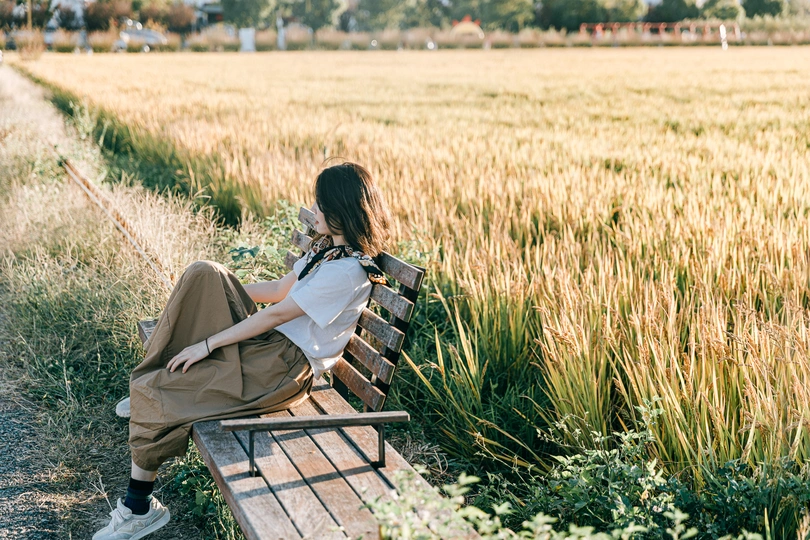 一位年轻女子坐在麦田里的木凳上