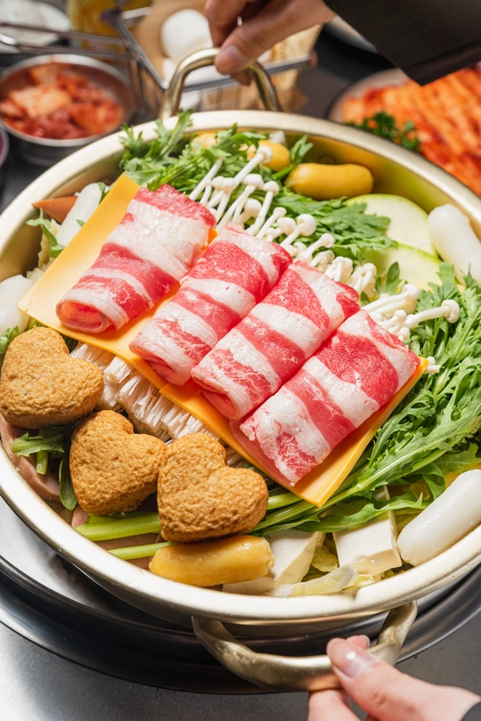 一个盛满绿色蔬菜和肉类的大碗 旁边是桌子上的一盘食物