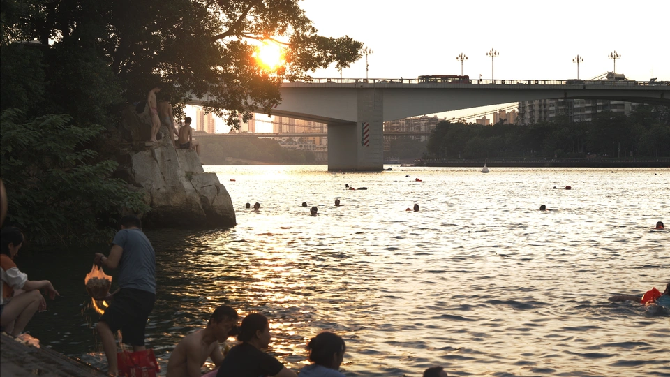 夕阳下在河中游泳的人们 背景中有桥。