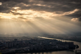 夕阳下城市和河流的 aerial view 阳光穿过云层