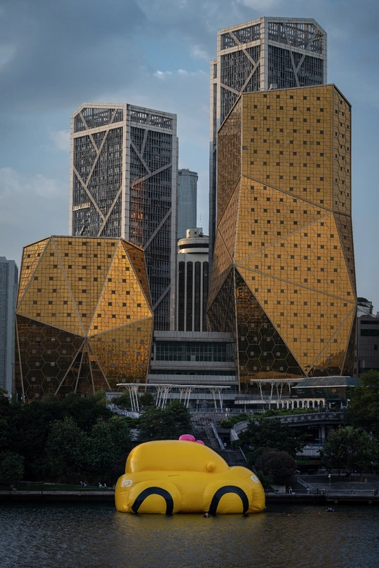 一辆黄色汽车在水中有大型建筑物的背景