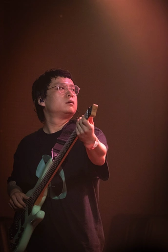 一个戴眼镜的男人在黑暗的房间里舞台上弹吉他 手里拿着手机