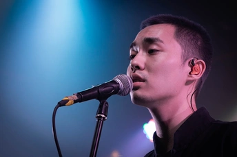 乐队中的一个年轻人在舞台上对着麦克风唱歌