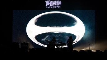 一个人在音乐会舞台上表演 前面有一个发光的屏幕。