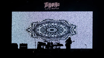 一个人在演唱会上表演 舞台上有一个大屏幕。