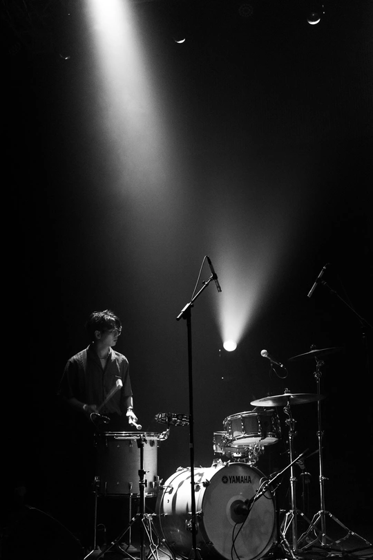 一个黑白图像 描绘了一个夜晚在舞台上演奏乐器的人 在聚光灯下。