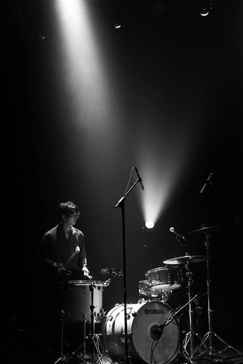 一个黑白图像 描绘了一个夜晚在舞台上演奏乐器的人 在聚光灯下。