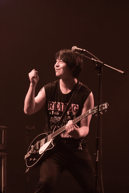 一个黑白图像 描绘了一个年轻男子在夜晚舞台上演奏乐器。