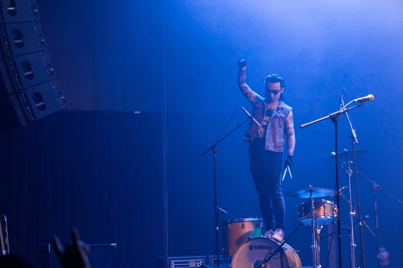 舞台上有一个男人在乐队中表演鼓 乐队在观众面前演出。