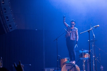 舞台上有一个男人在乐队中表演鼓 乐队在观众面前演出。