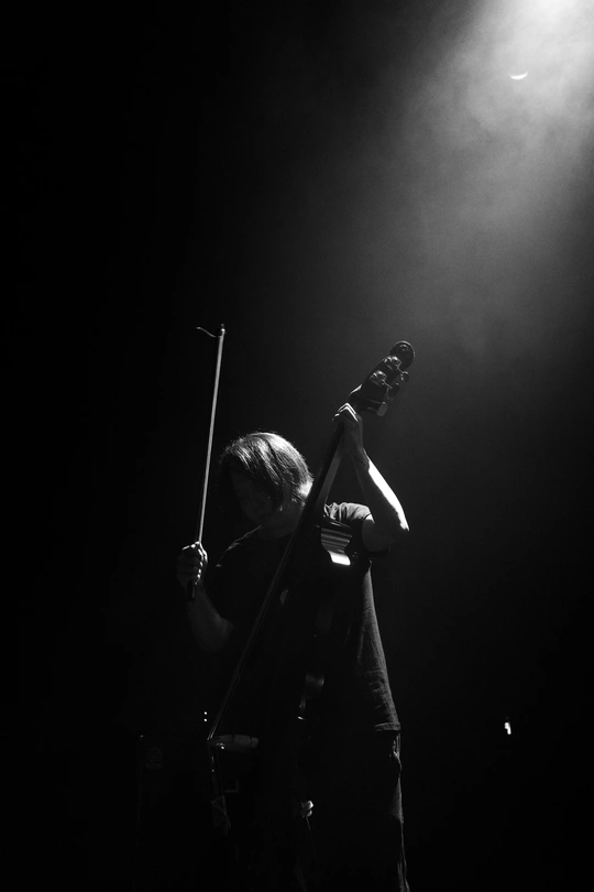 一个黑白图像 描绘的是一个人在夜晚舞台上演奏乐器。