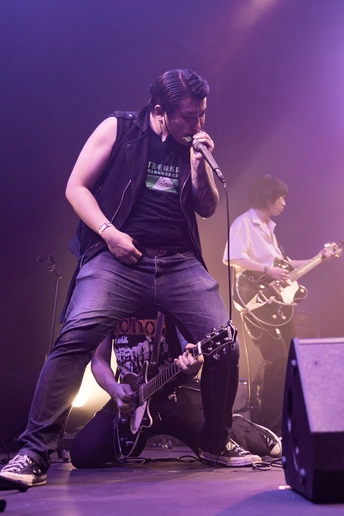 图片可能包含一个人在舞台上演奏乐器 比如吉他 还有麦克风 在音乐会现场。