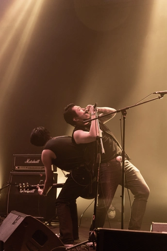 图片可能包含演奏乐器的人、乐队、麦克风和吉他 在舞台上。