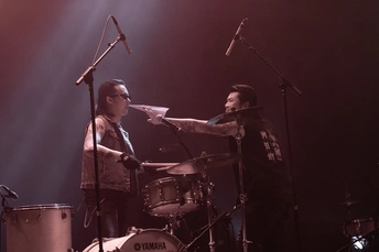 一个人在舞台上演奏乐器 与乐队一起 演奏鼓并拿着麦克风