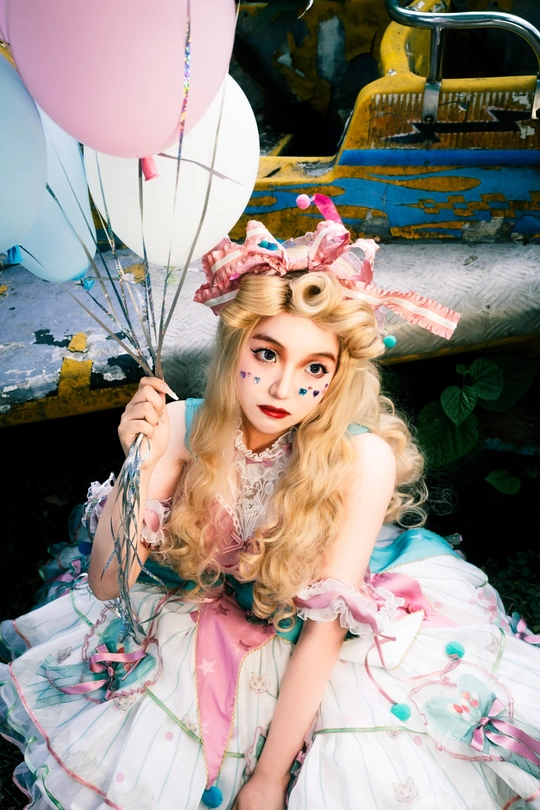 一位穿着粉红色和白色连衣裙的女士拿着一束气球