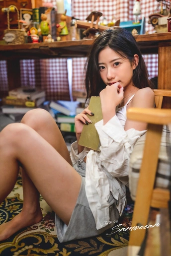 一位年轻女子坐在椅子上 坐在地板前一张桌子旁边。