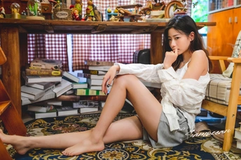 一个年轻女子坐在椅子上 双腿交叉在脏乱的书房地板上。