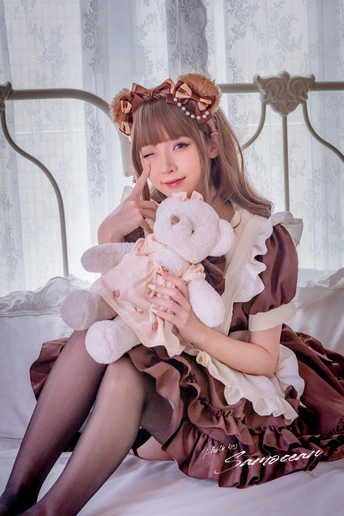 一个穿着维多利亚式卧室风格衣服的年轻女子坐在床上抱着一只小熊