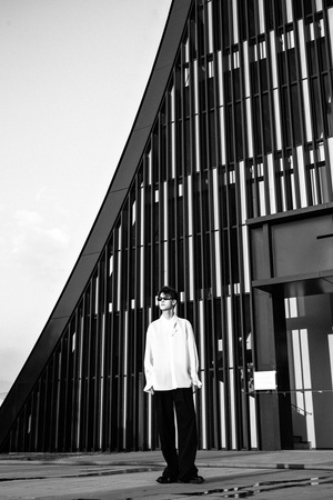 一张年轻人站在高楼大厦前的黑白照片