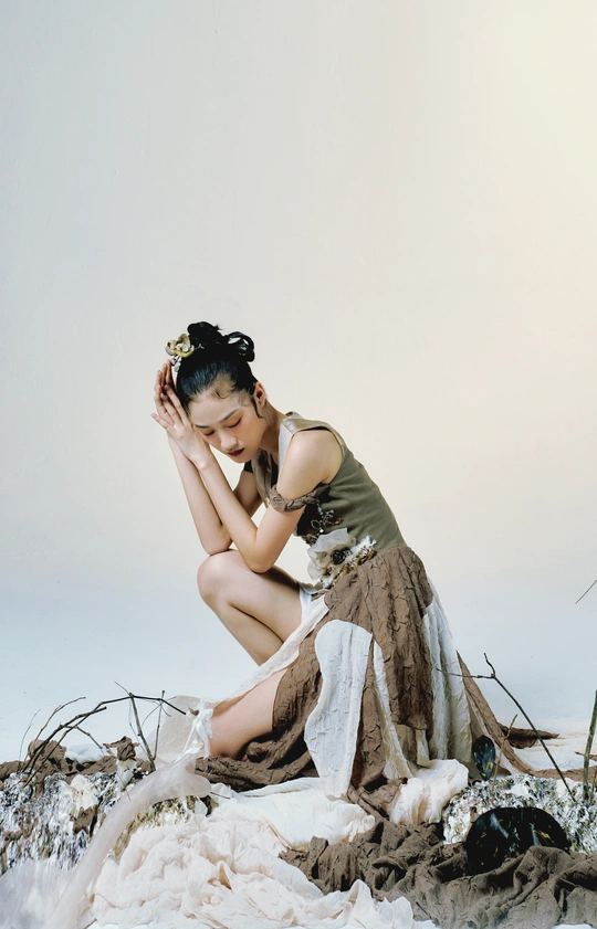 一个年轻女子坐在雪地里 双手放在裙子里