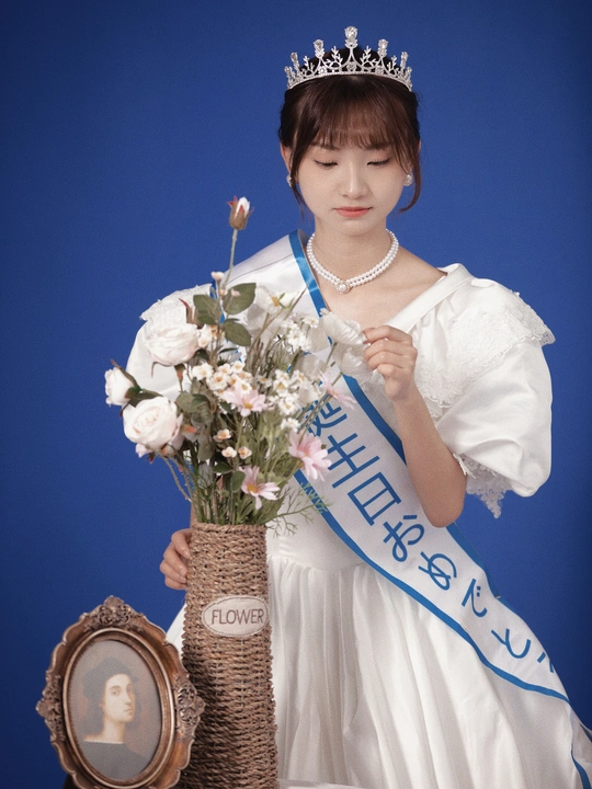 一位身穿白色连衣裙、头戴王冠的年轻女士手里拿着一束鲜花和一个篮子 篮子里有一个人穿着连衣裙的照片