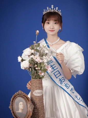 一位身穿白色连衣裙、头戴王冠的年轻女子手里拿着一束鲜花和一个篮子 篮子里有一个人穿着连衣裙的照片